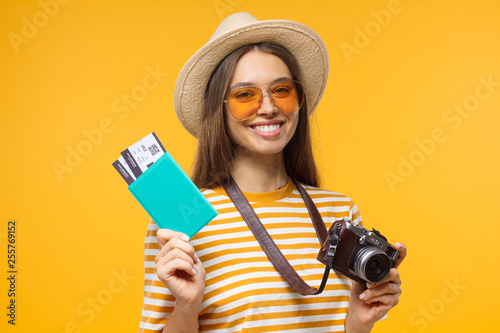 Fotomural Excited cheerful young tourist girl holding passport with tickets and camera, is