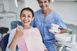 © Yakobchuk Olena - Charming lady doing thumbs up sign while dentist standing behind her