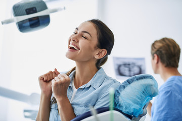 Wall Mural - Young lady feeling happy while sitting in dental chair