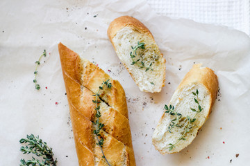 French baguettes and cut slice with thyme on kraft paper. Top view food, close up