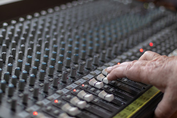 Adult man hand controlling the sliders of a mixer in a studio