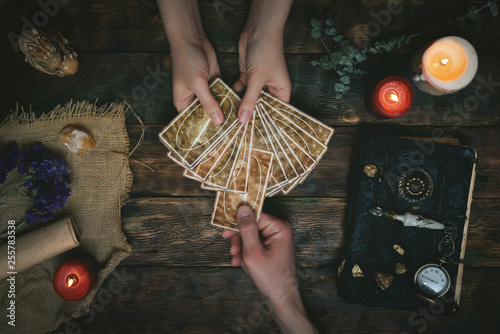 Cuadros en Lienzo Tarot cards, magic book and fortune teller hands on a wooden table background