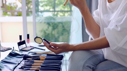 Wall Mural - Young woman sitting on sofa and doing makeup at home