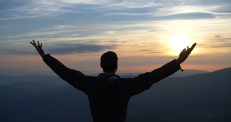 Man on the top of the world praying to god at sunset