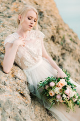 Stunning bride in beautiful wedding dress on rock background.