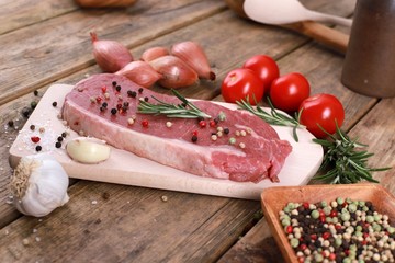  raw fresh meat steak - rumpsteak  with rosemary, pepper, tomatos and spices on a rustic wooden table