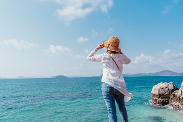 Wall Mural - Back view of young asian woman looking from cliff. Future and research concep. Happy woman with hands up standing on cliff over sea. Travel mood, concepts of winner, freedom, 