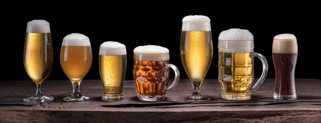 Canvas Print - Beer assortment. Cold different glasses of beer on the wooden table at the black background.