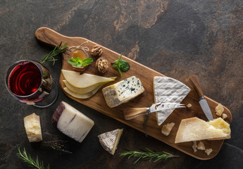 Wall Mural - Cheese platter with organic cheeses, fruits, nuts and wine on stone background. Top view. Tasty cheese starter.
