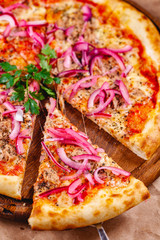 Wall Mural - Pizza with tuna and red onion on wooden cutting board. Close up