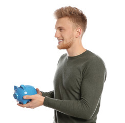 Wall Mural - Young man with piggy bank on white background