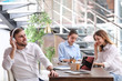 © New Africa - Young businessman with headphones, laptop and his colleagues at table in office
