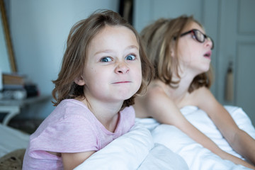 sisters in mum and dads bed in the morning watching tv