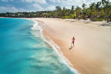 Aerial View Of The Running Young Woman On The White Sandy Beach Near Sea With Waves At Sunrise. Summer Holiday. Top View Of Sporty Slim Girl, Clear Azure Water. Indian Ocean. Lifestyle And Sport