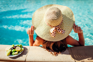 Woman in bikini eating fruits and relaxing in swimming pool. All inclusive. Summer vacation