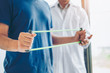 © joyfotoliakid - Physiotherapist man giving resistance band exercise treatment About Chest muscles and Shoulder of athlete male patient Physical therapy concept