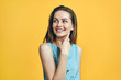 Young smiling beautiful woman looking up on yellow background