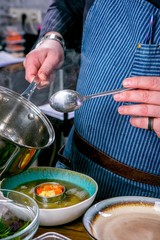 Chef decorates the soup Fo Bo from smoked catfish with cellophane noodles. Master class in the kitchen. The process of cooking. Step by step. Tutorial. Close-up