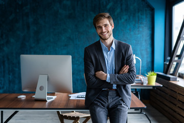 Wall Mural - Businessman wearing modern suit and stands in contemporary office.