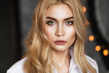 Portrait of a young beautiful girl in a white shirt looking into the camera, closeup.