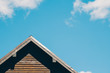 Close up of triangular roof of modern log house against bright blue sky with white clouds. Copy space