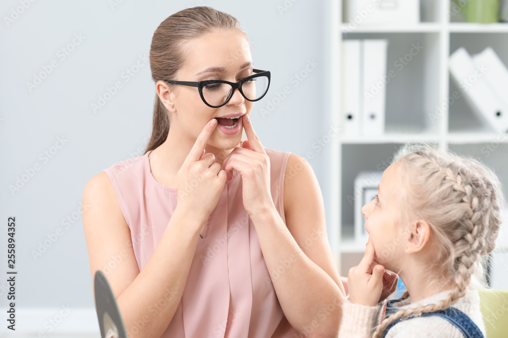 Speech therapist working with little girl in office
