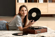 © Pixel-Shot - Young woman with old record player and vinyl discs at home
