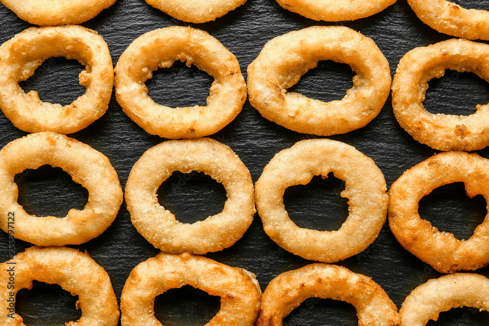 Tasty onion rings on dark background