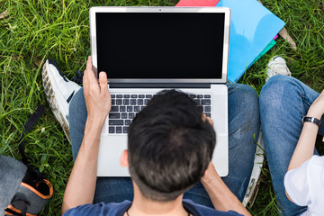 Wall Mural - Top view young students sitting on grass with laptop and book