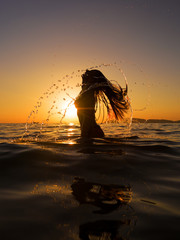 Sticker - Woman in the sea at sunset flipping her hair out of the water