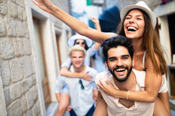 Happy friends enjoying piggyback while sightseeing in the city.