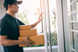 © wutzkoh - Young asian courier is using the hand of the knock at the door to deliver the goods.