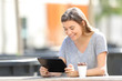 © Antonioguillem - Happy teenage girl using a tablet sitting in a park