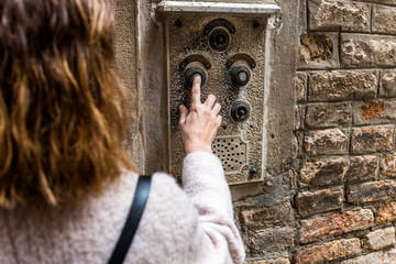 Woman pushing ancient intercom in Venice, taly