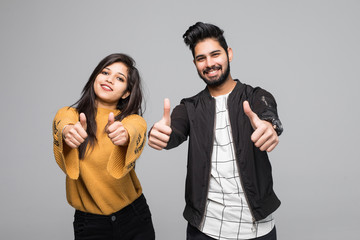 Happy young indian couple showing thumbs up and looking at camera isolated over gray background