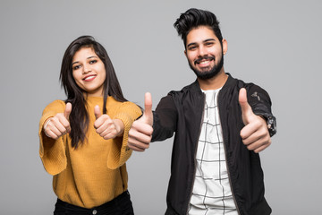 Wall Mural - Happy young indian couple showing thumbs up and looking at camera isolated over gray background