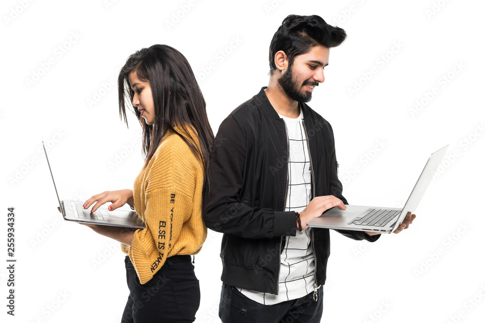 Portrait of a young indian couple holding laptops computer while ...