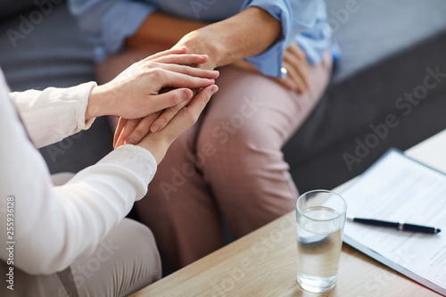 Fotomural Young psychologist holding hand of her patient in need while consulting her afte