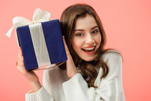 Smiling And Beautiful Woman In White Sweater Holding Gift Box Isolated On Pink