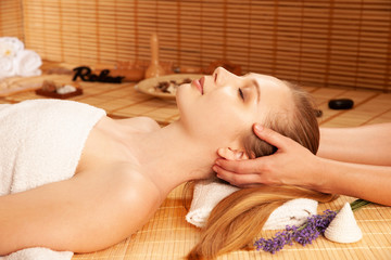 Beautiful young woman having a face massage in spa salon - wellness