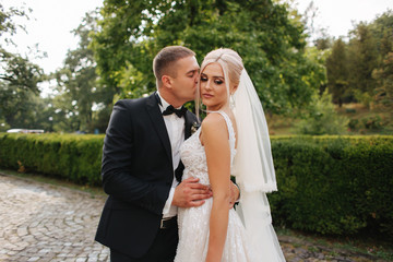 Beautiful wedding couple walking in the park. Bride with long white dress and stylish groom