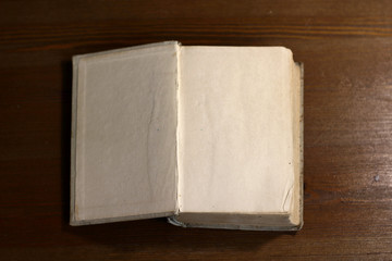 Fototapete - An open old retro book with white blank empty pages on which the designer can write a greeting text or a postcard on the wooden background of the library atmosphere