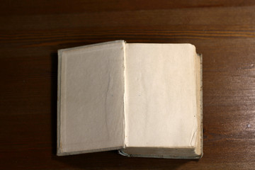 Fototapete - An open old retro book with white blank empty pages on which the designer can write a greeting text or a postcard on the wooden background of the library atmosphere
