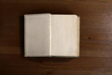 Fototapete - An open old retro book with white blank empty pages on which the designer can write a greeting text or a postcard on the wooden background of the library atmosphere