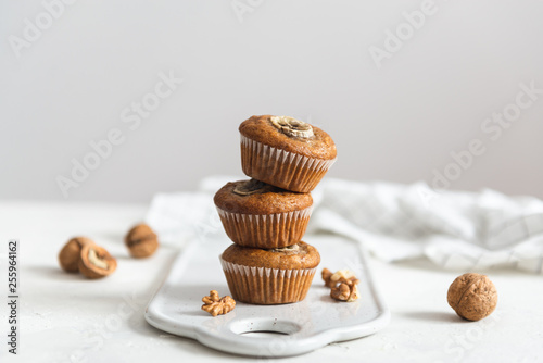 Fotomural Stack of Homemade banana muffins with walnut on white background, copy space