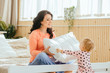 © Iryna - Caucasian brunette mother and little toddler daughter having fun with pillow on bed. Baby giving the pillow her mothrer.