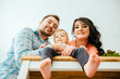 © Iryna - A low-angle view of young family with a barefoot toddler girl moving in new home at kitchen table.