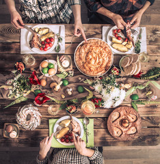 Holiday friends or family at the holiday table with rabbit meat, vegetables, pies, eggs, top view.