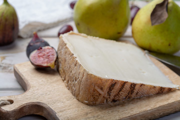 Piece of French cheese Tomme de Brebis made from sheep milk served as dessert with fresh figs and pears