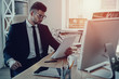 © gstockstudio - New contract. Serious young man in formalwear reading contract while sitting in the office